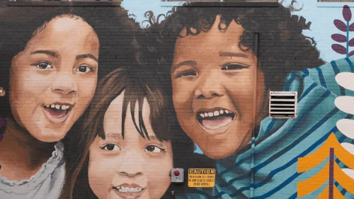 Large mural paiting on building, with smiling children