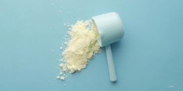 A scoop of vanilla protein powder on a blue background