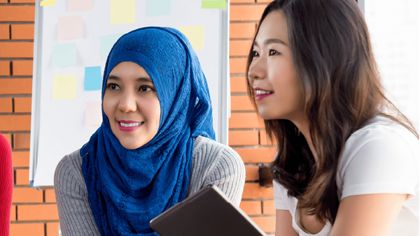 Two women engaged in conversation, one wearing a blue hijab