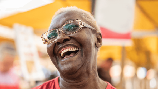 Older person of color with glasses smiling at an event