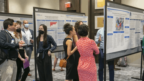 Session-goers reviewing all of the posters on display in a lobby.