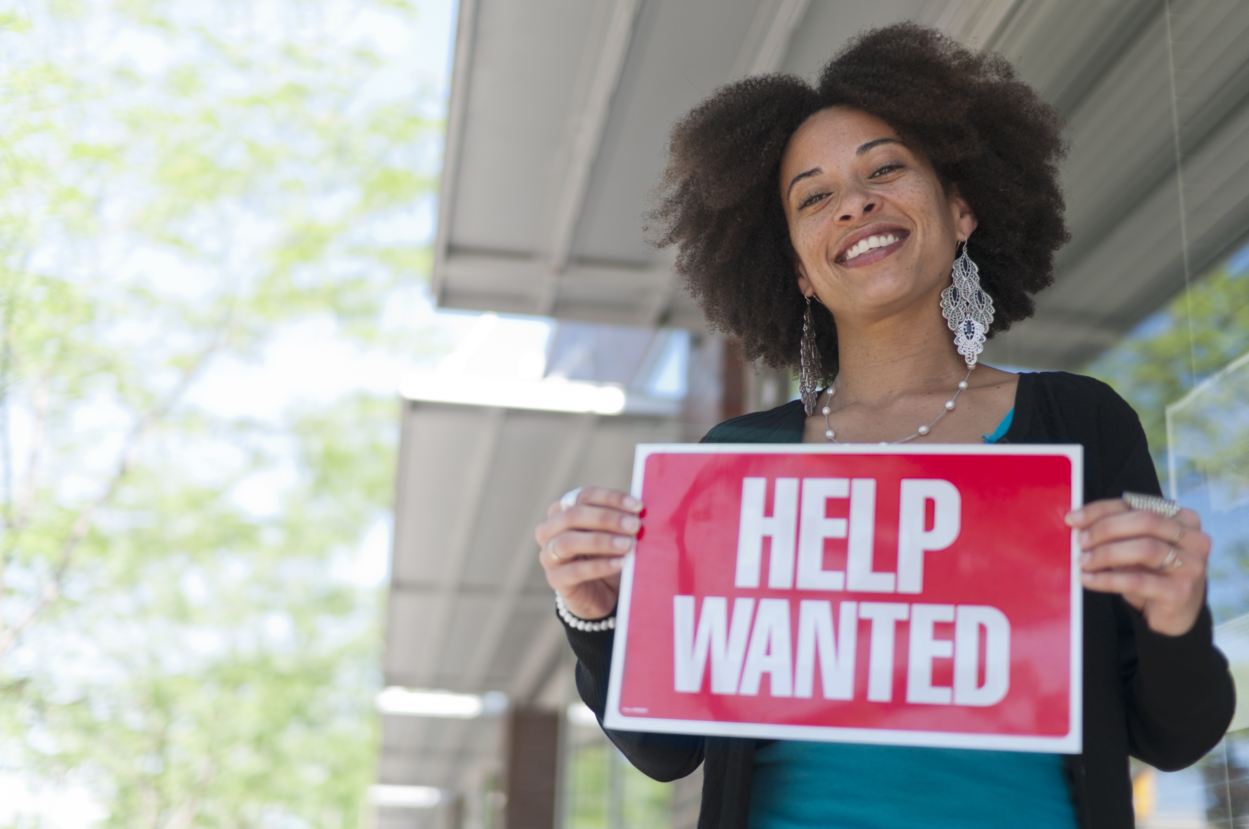 A woman holding a help wanted sign