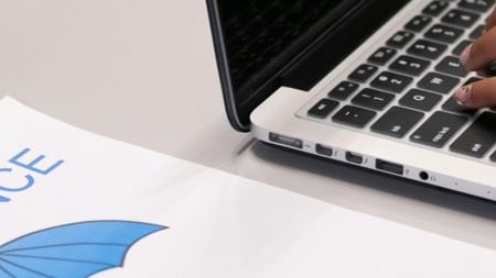 Photo of a laptop computer and a hand typing on it