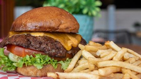 Photo of a large juicy cheeseburger and french fries